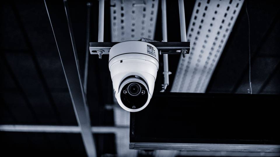 كاميرا قبة بيضاء معلقة من سقف داخلي بجانب مجاري الكابلات