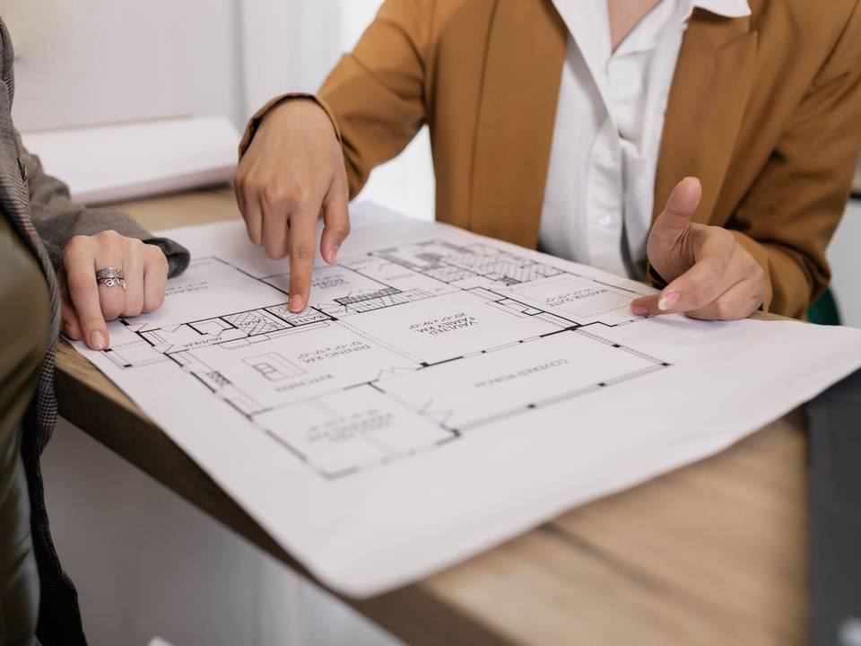 شخصان يراجعان مخططاً هندسياً لطابق على طاولة